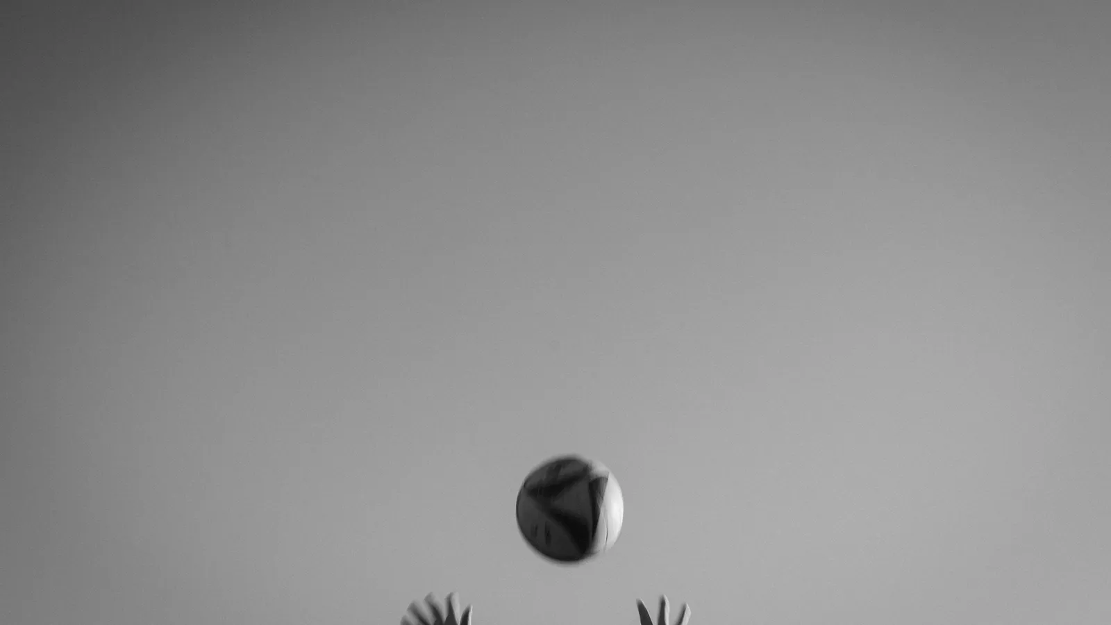 A ball tossed into the air above outstretched hands