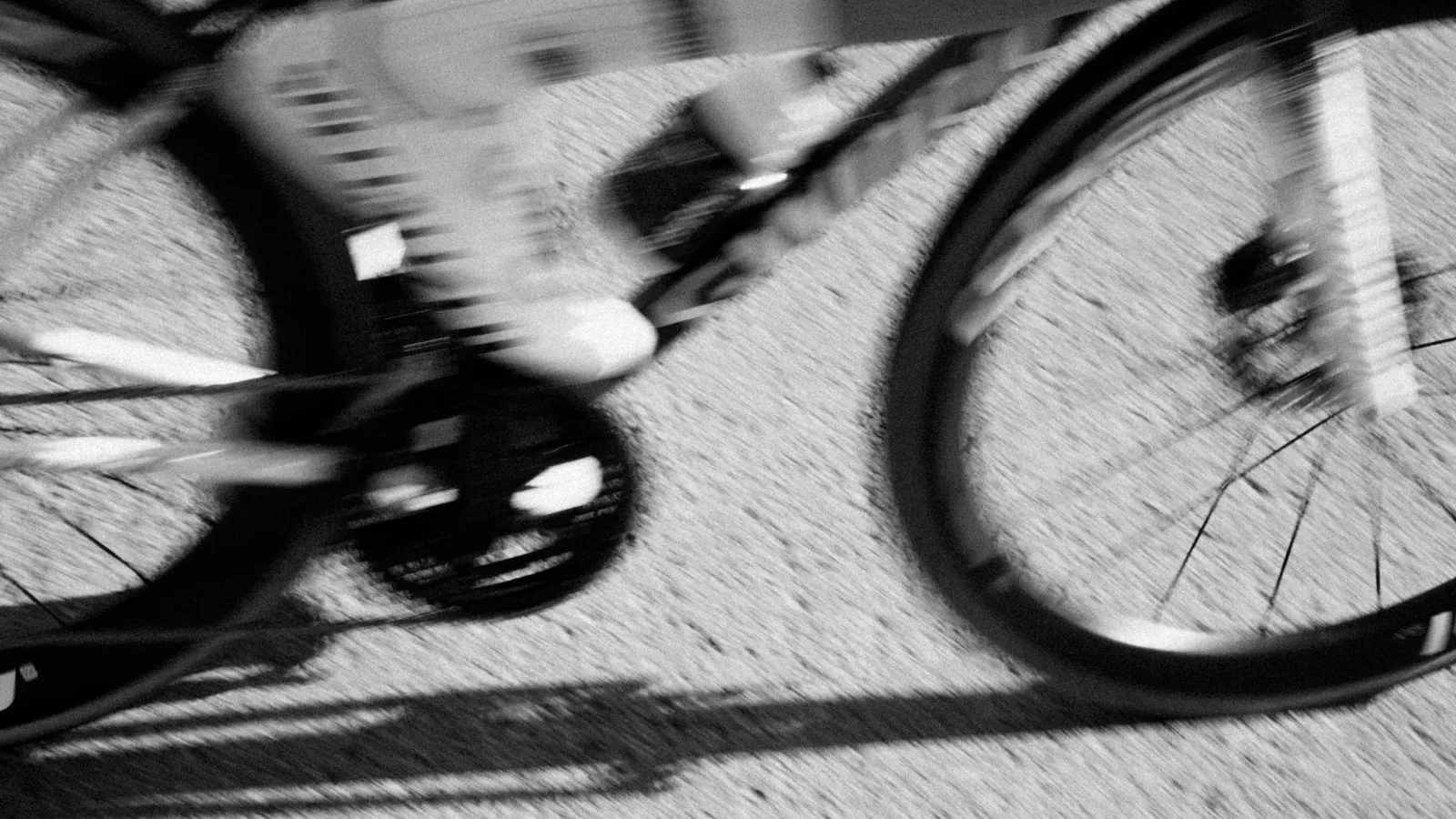 A bicycle wheel rolling along the road, in black and white