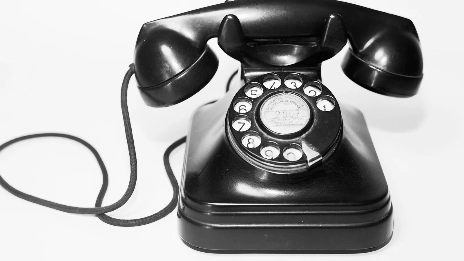 A black rotary-dial telephone with its handset lifted