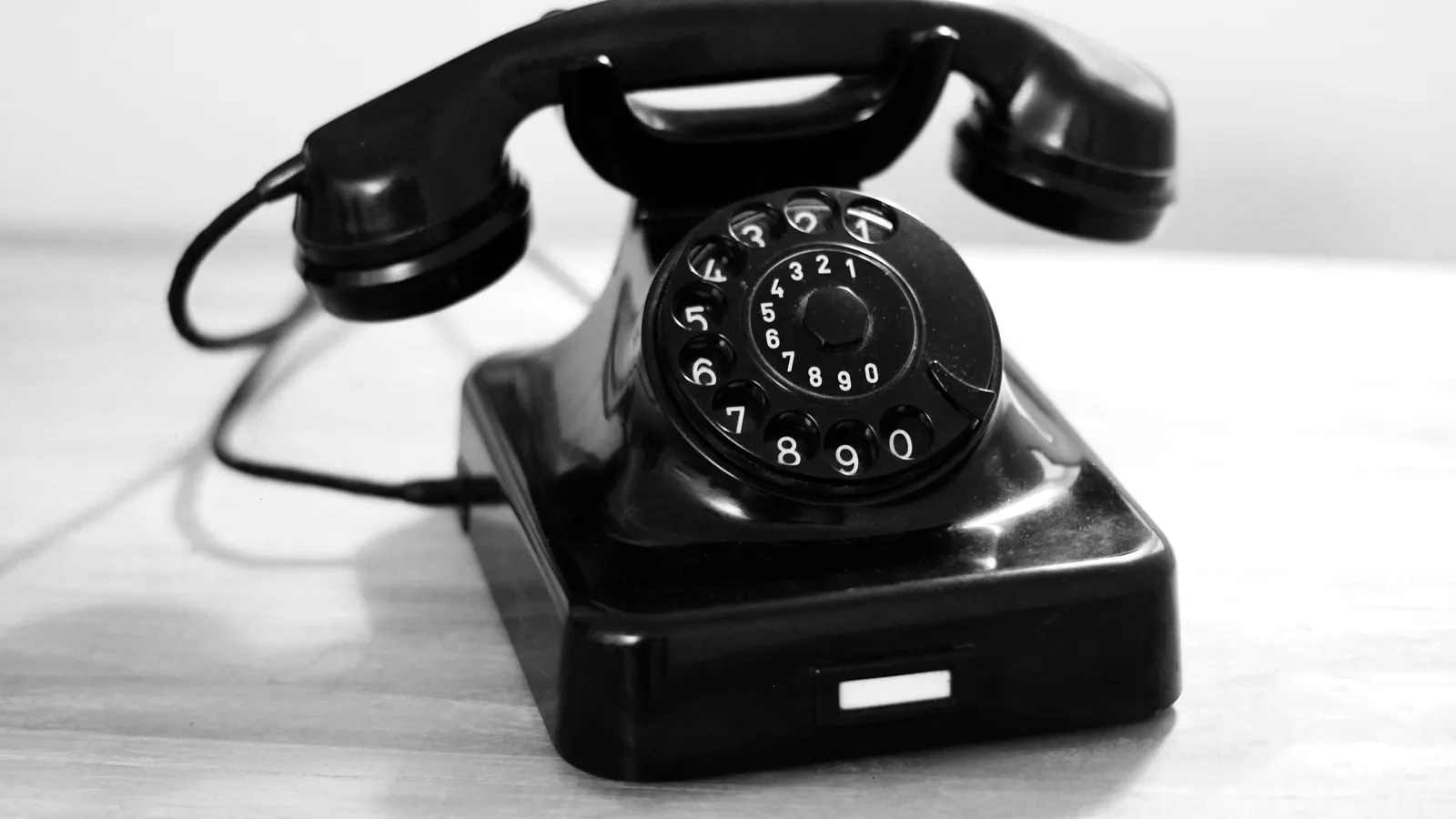 A black rotary telephone with its handset on the cradle