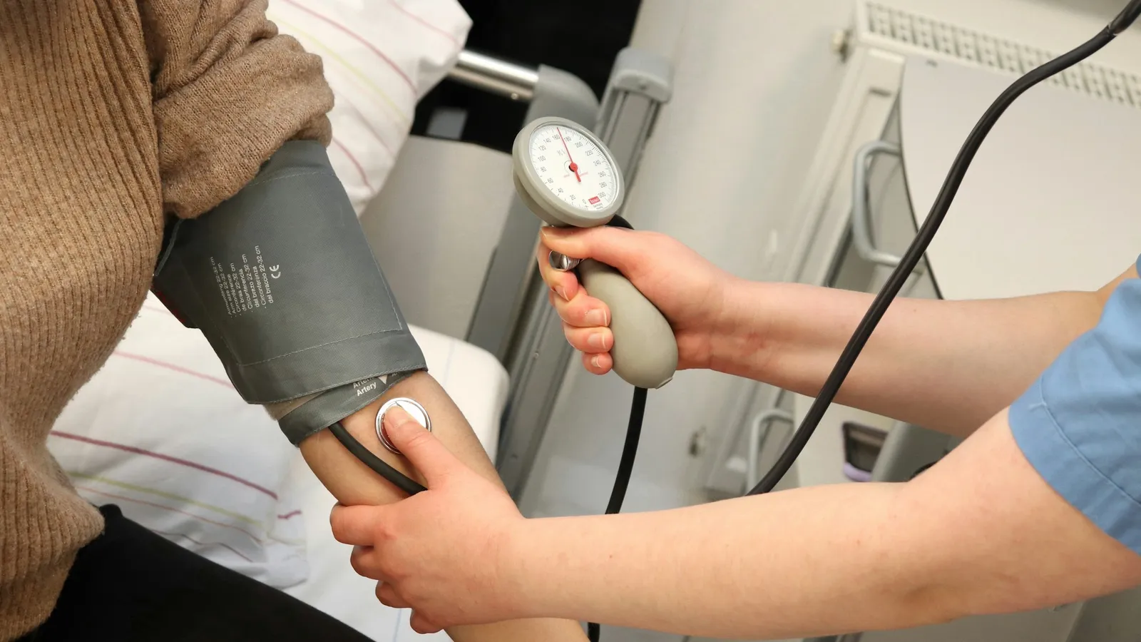 A blood pressure cuff being fitted on an arm