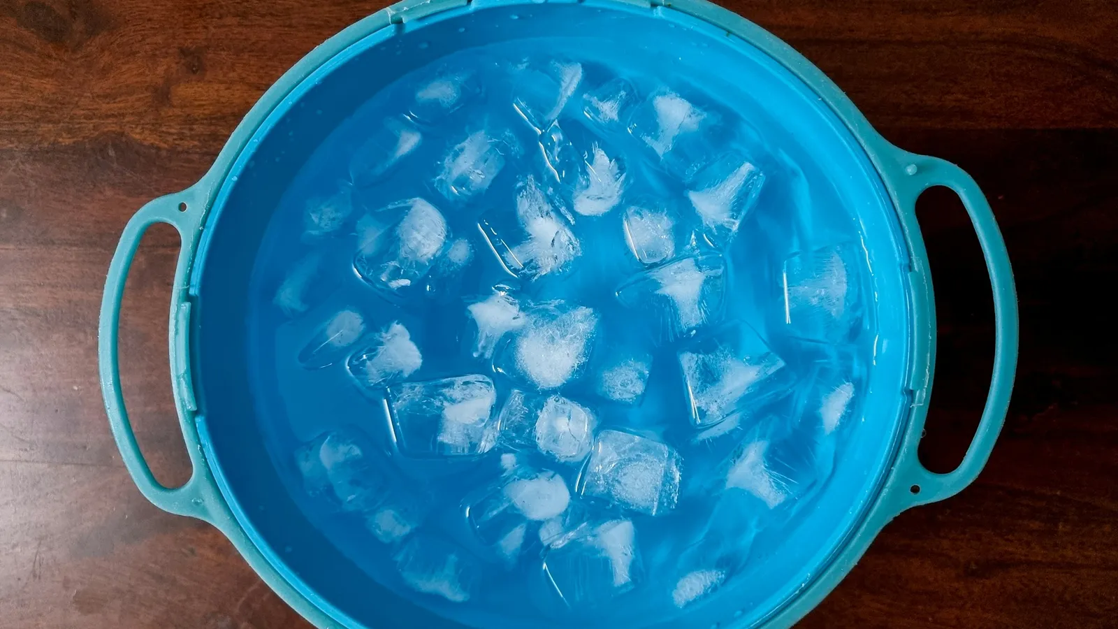 A blue bowl full of ice cubes, seen from above