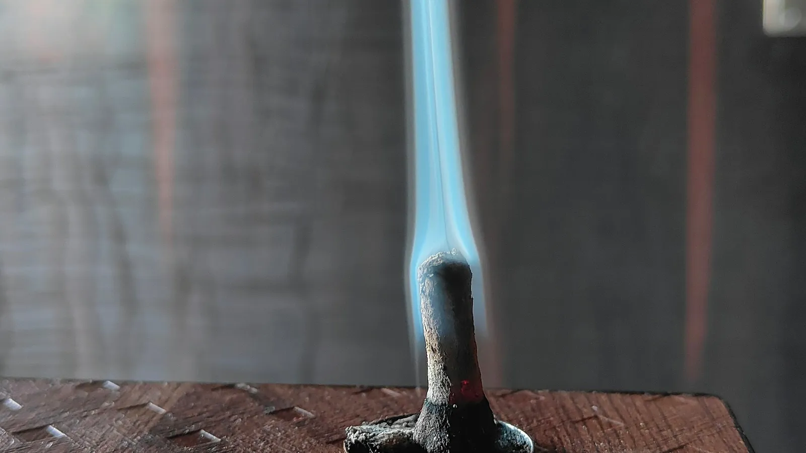 A blue Bunsen burner flame on a lab bench