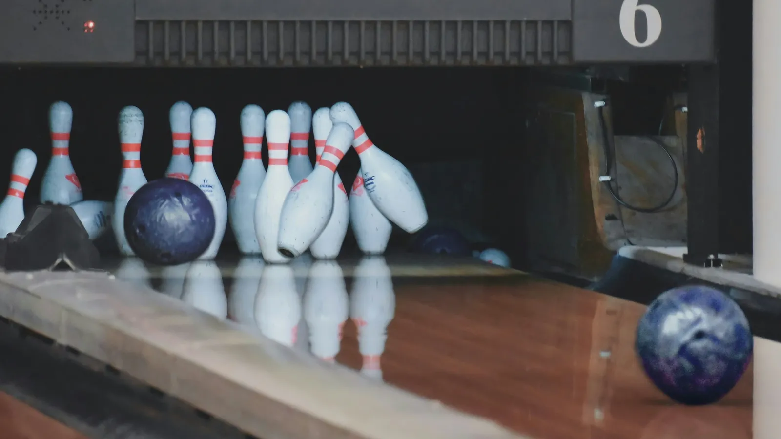 A bowling ball rolling toward white pins