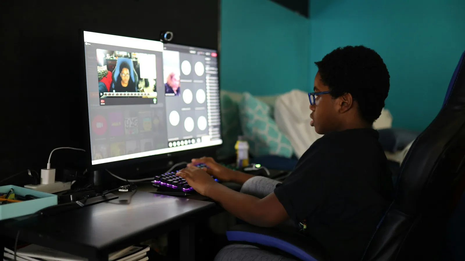 A boy at a desk watching a video on a large monitor