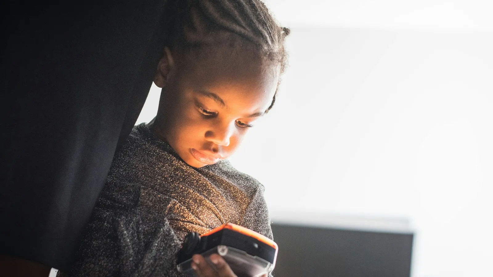 A boy in a sweater looking down at a smartphone