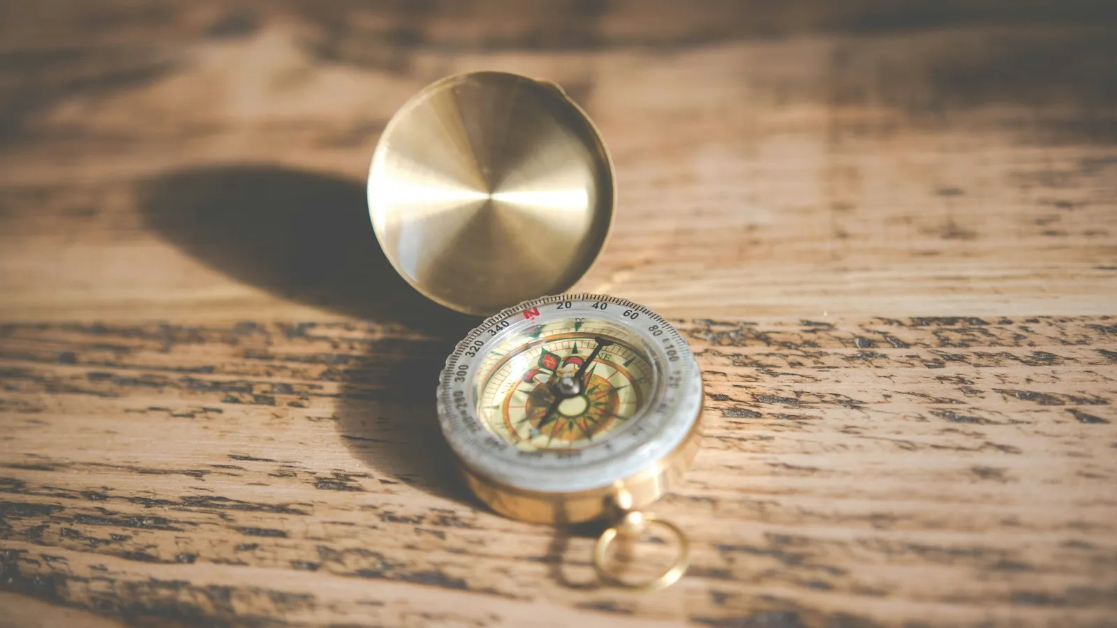 A brass magnetic compass on a wooden table