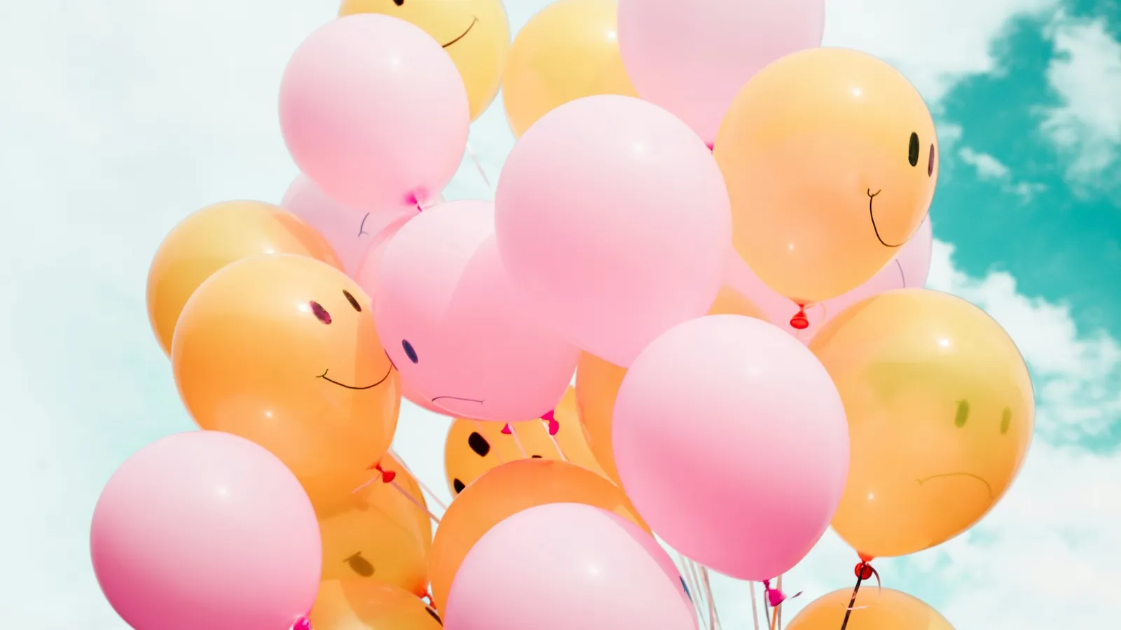A bunch of balloons floating against the sky