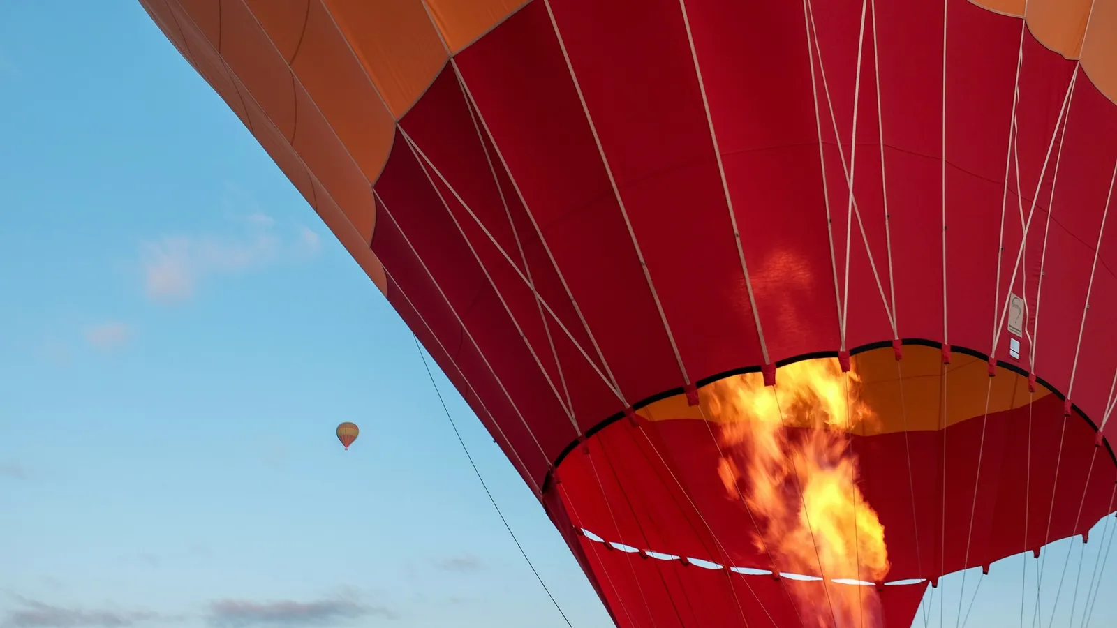 A burner flame heating the air inside a red balloon