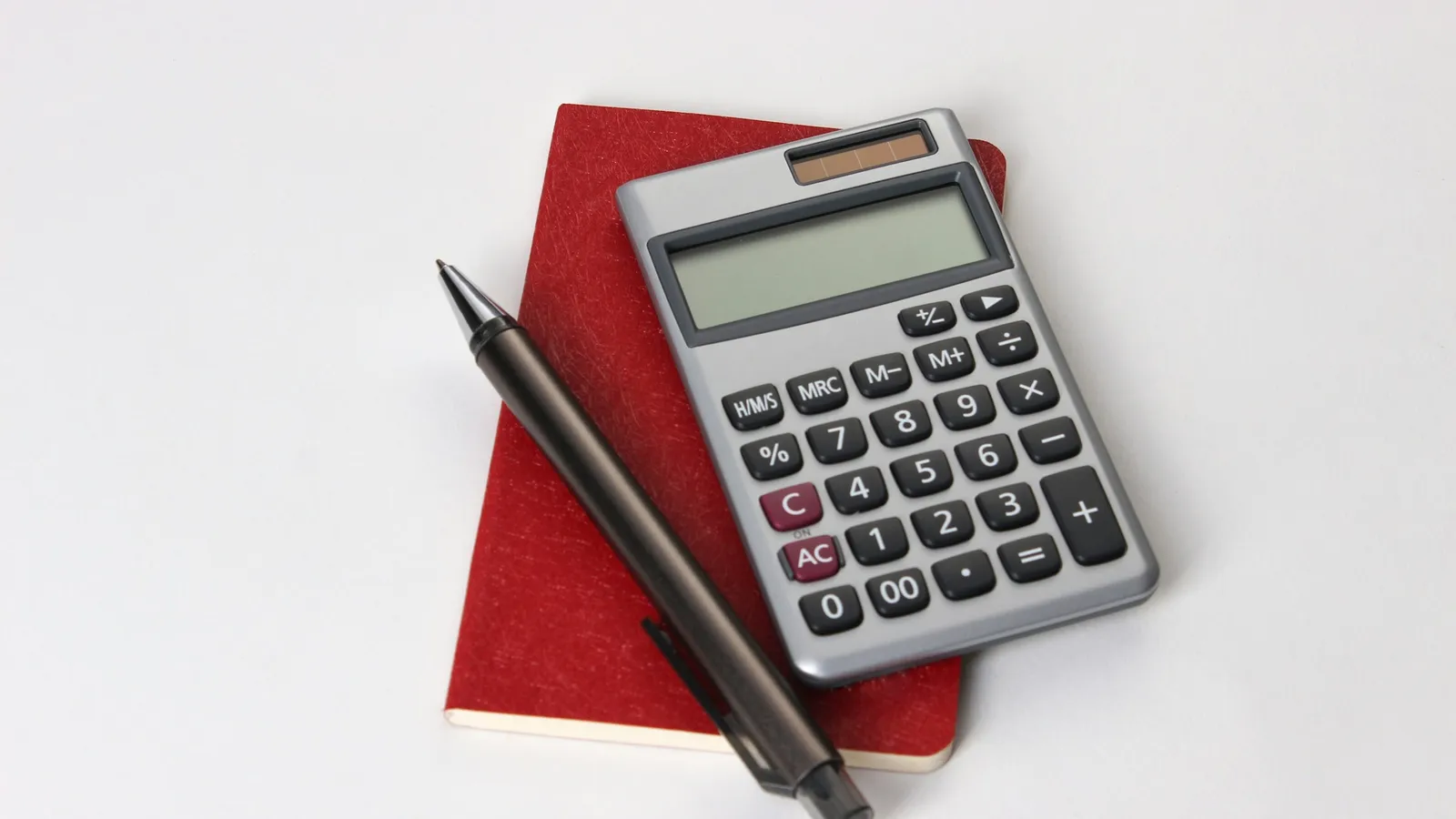 A calculator and pen on a red folder