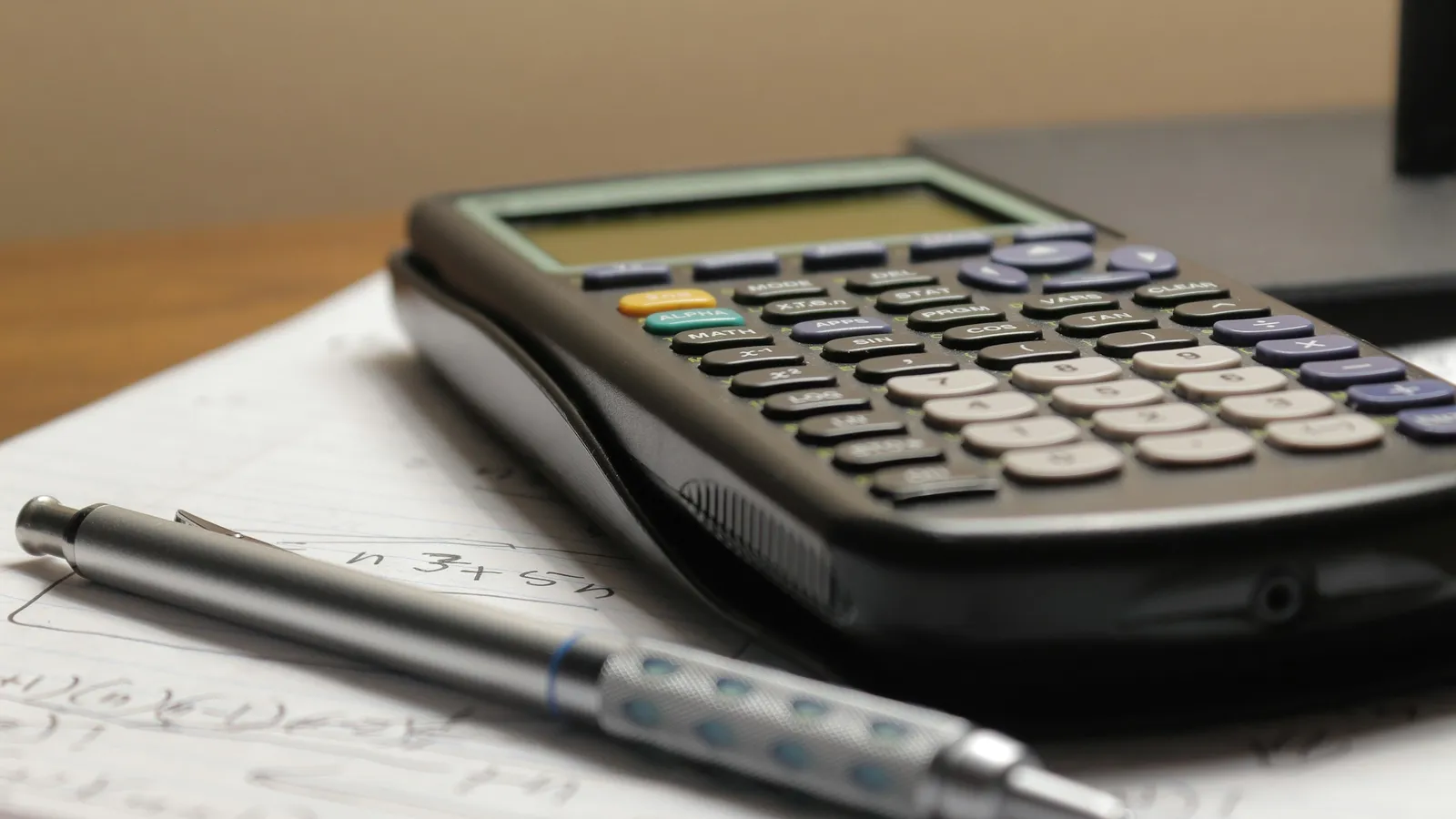 A calculator and pen resting on a sheet of paper