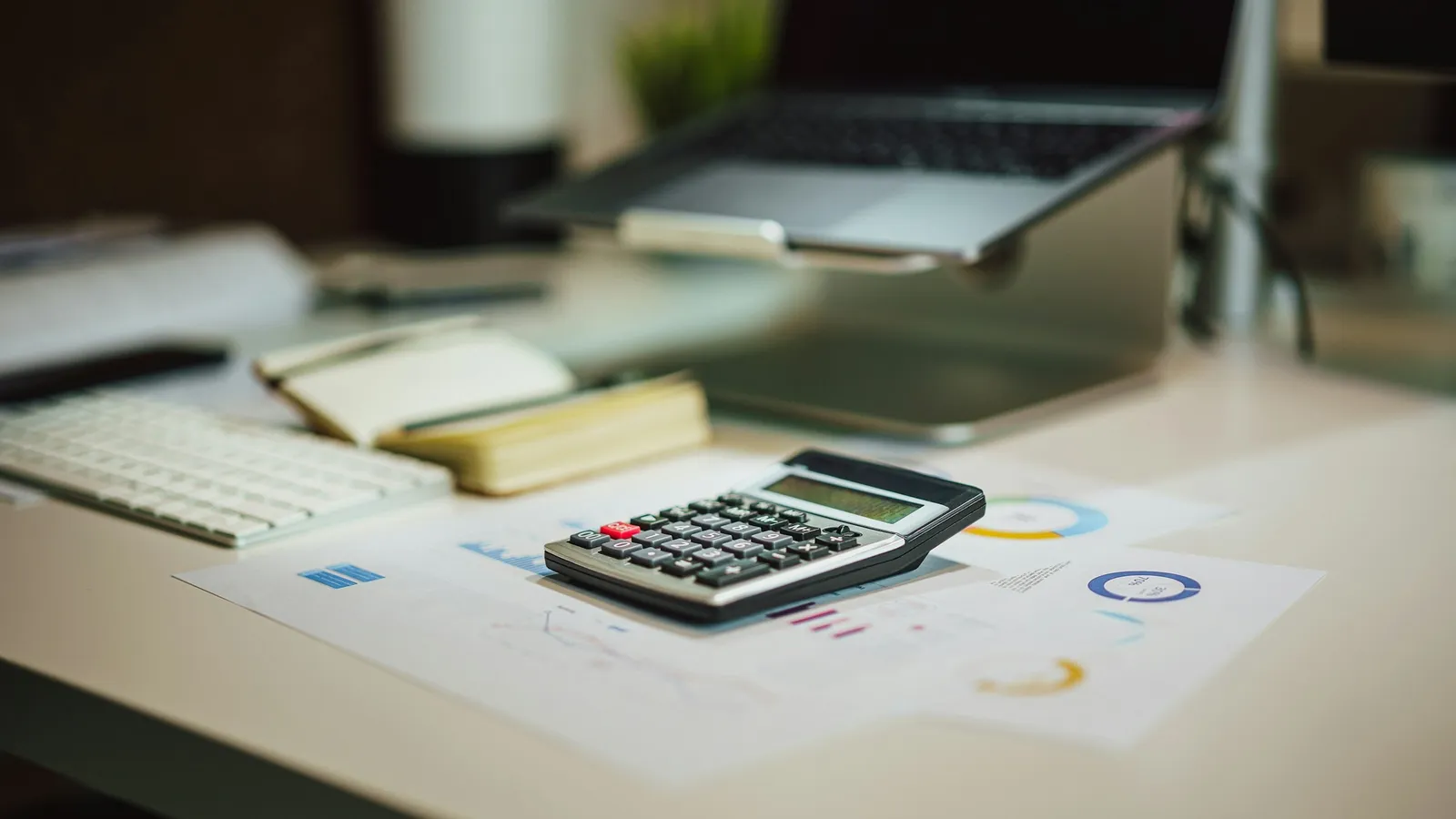 A calculator and pencil on a white desk with papers