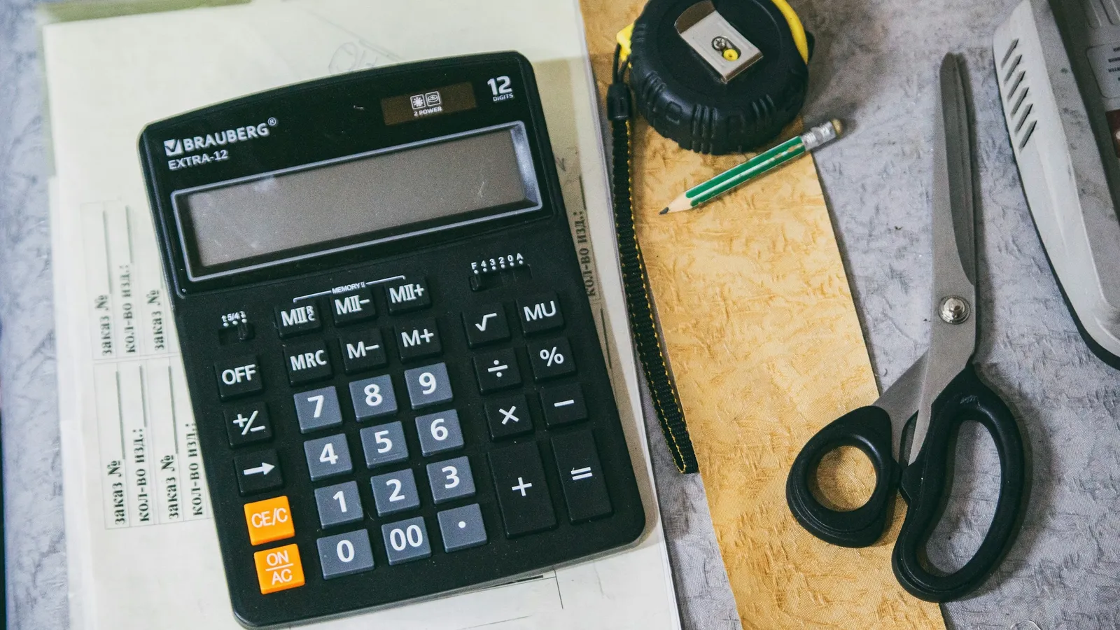 A calculator beside scissors and a notebook on a desk