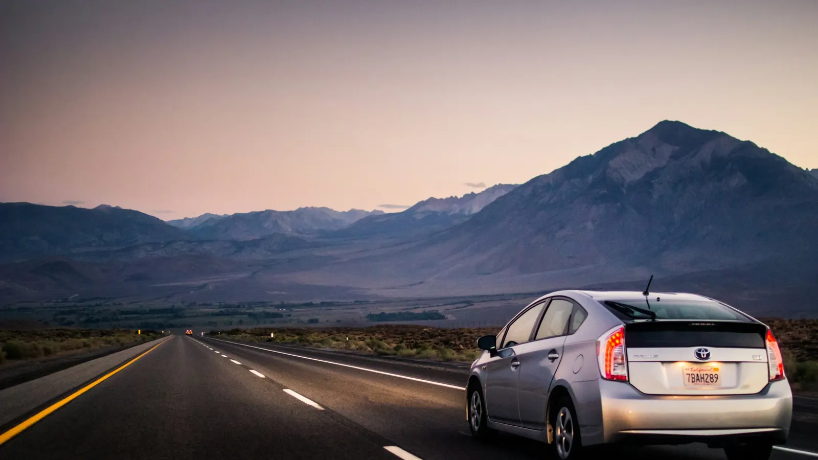 A car driving along an open road toward mountains