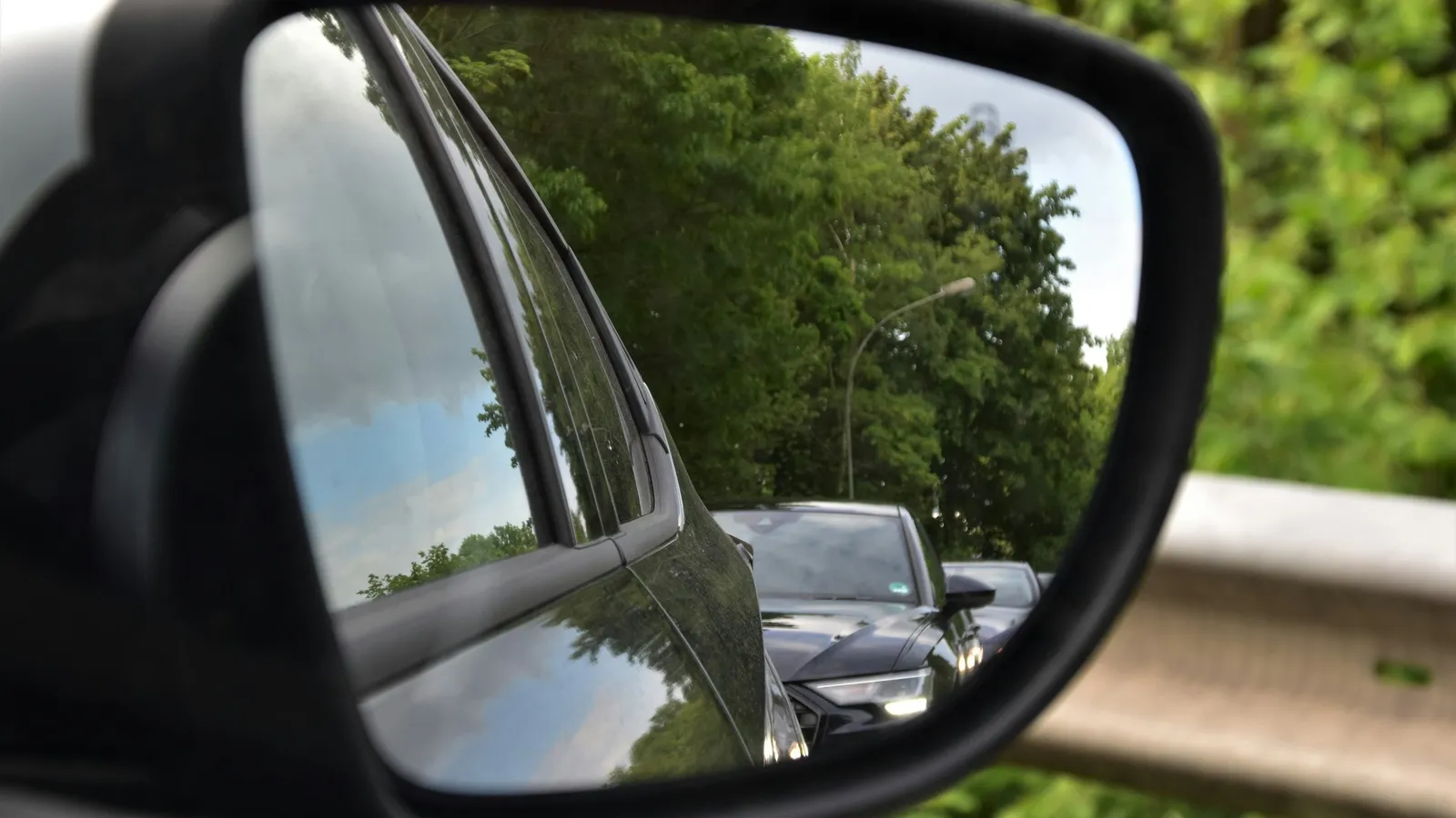 A car side mirror reflecting the road behind
