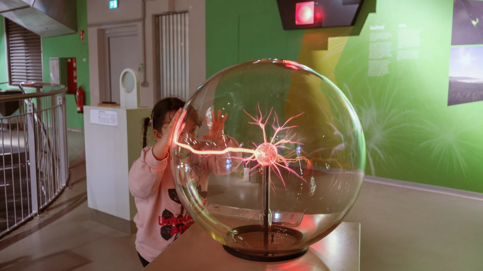 A child touching a glowing plasma ball at a science exhibit