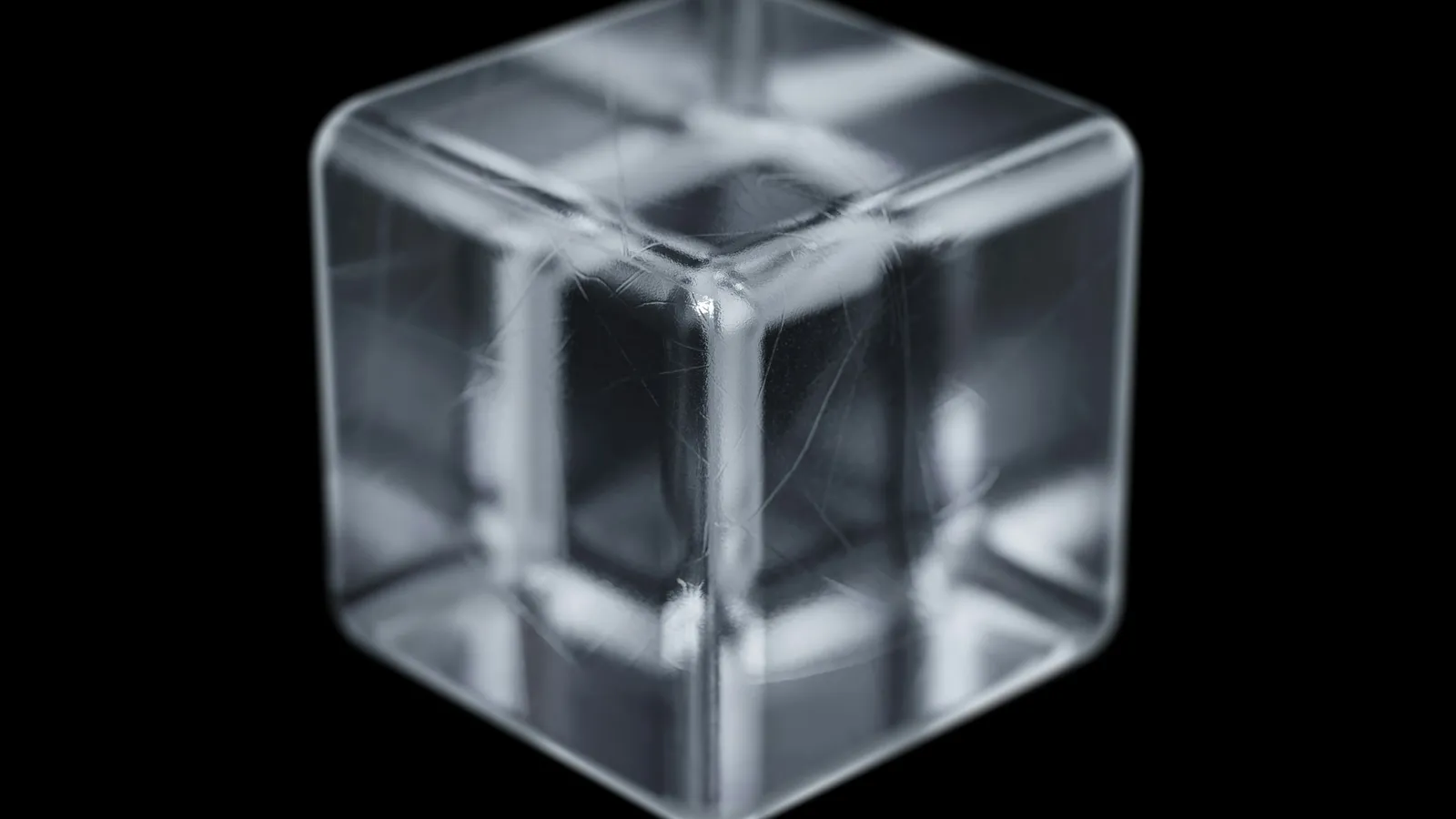 A clear glass cube bending light against black
