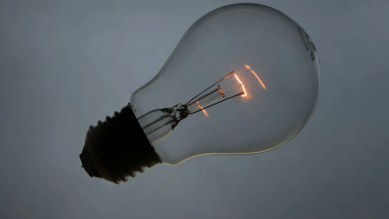 A clear glass light bulb with a glowing filament
