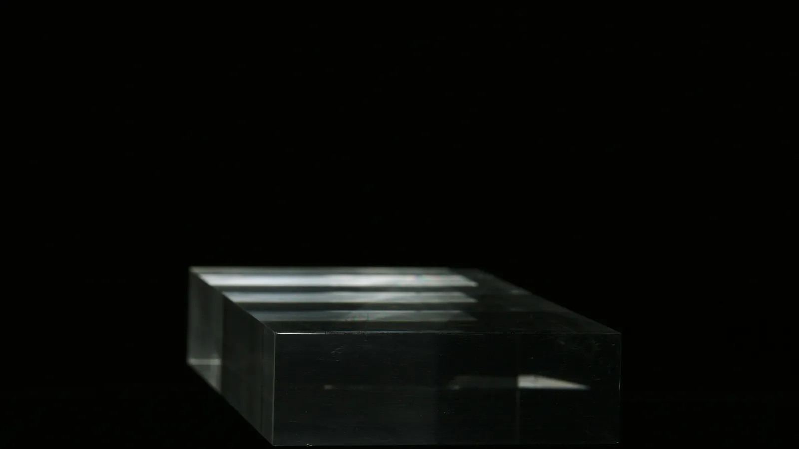 A clear rectangular glass block on black