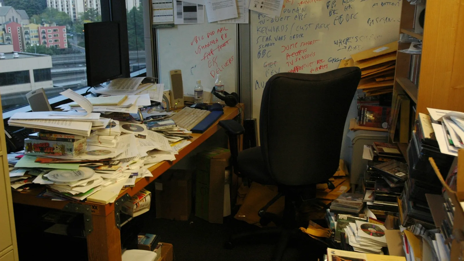 A cluttered desk piled with papers and books