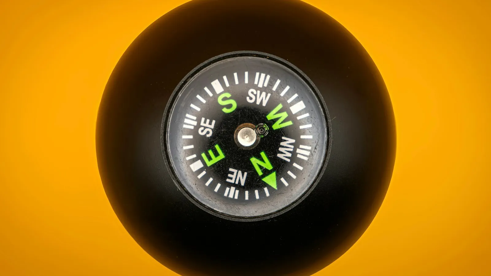 A compass held against a bright orange background