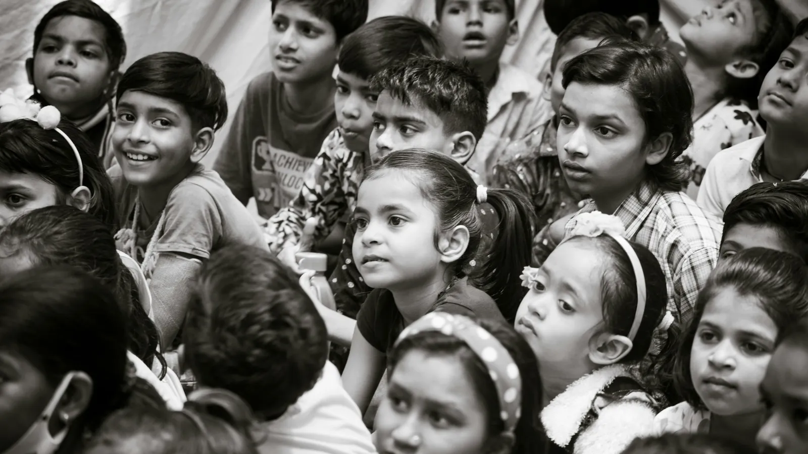 A crowd of schoolchildren looking up, in black and white