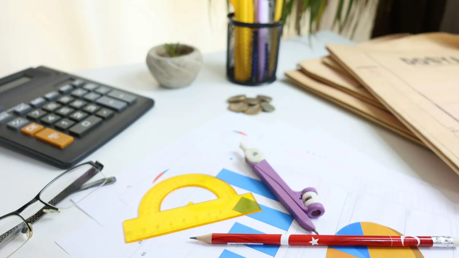 A desk with a calculator, protractors, rulers and coloured pencils