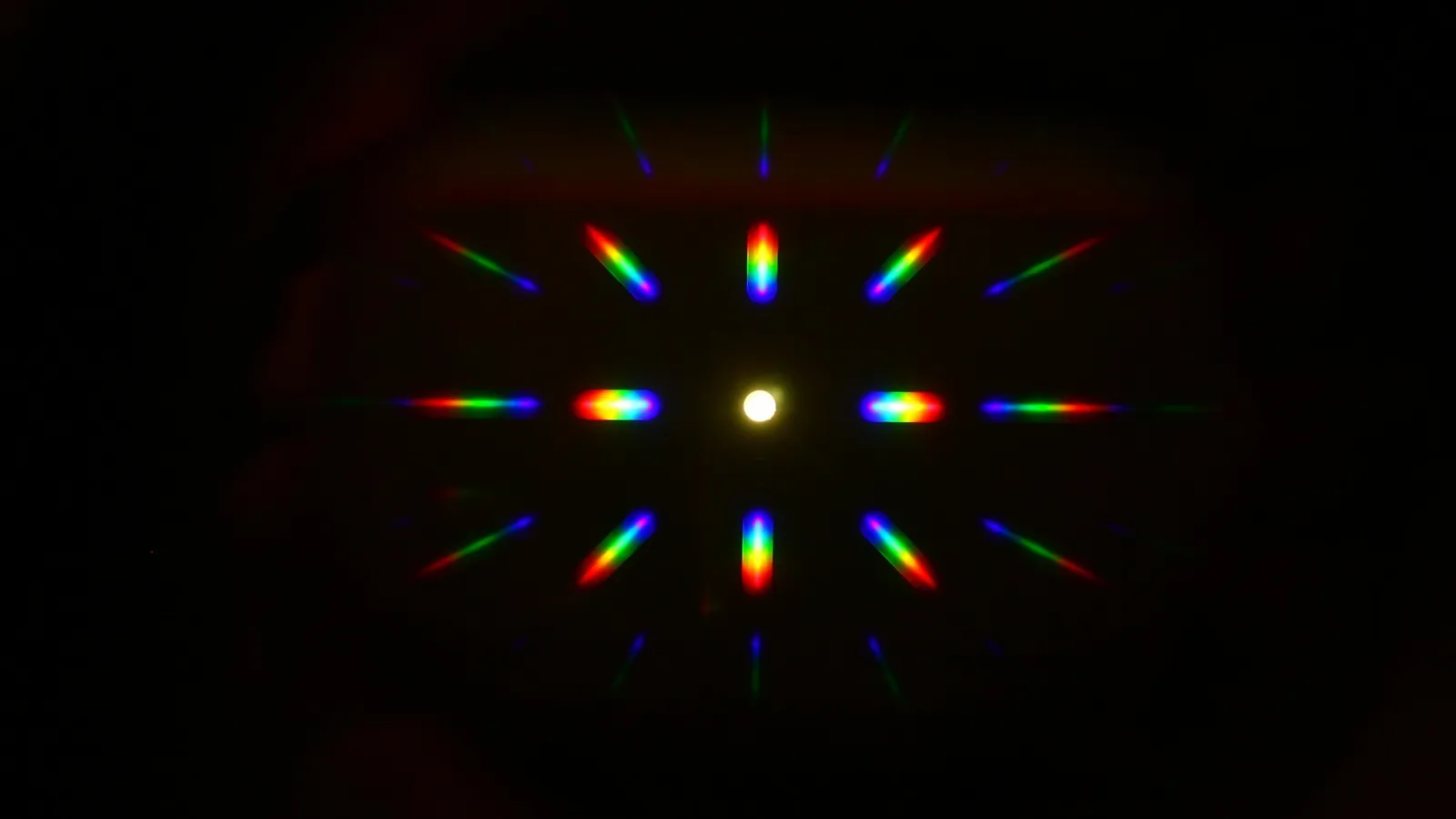A diffraction pattern of coloured light spots on a black background