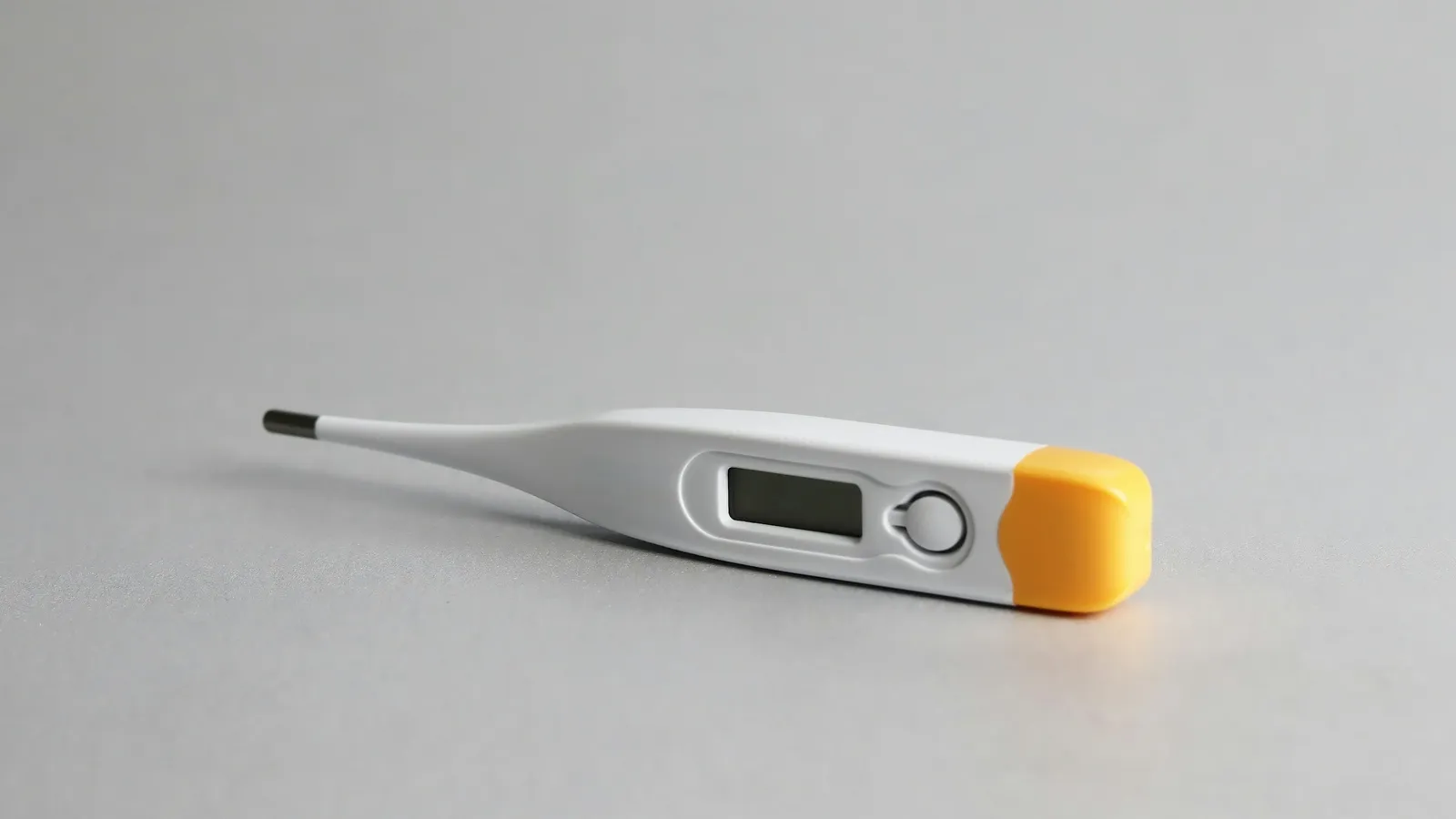 A digital clinical thermometer on a grey surface