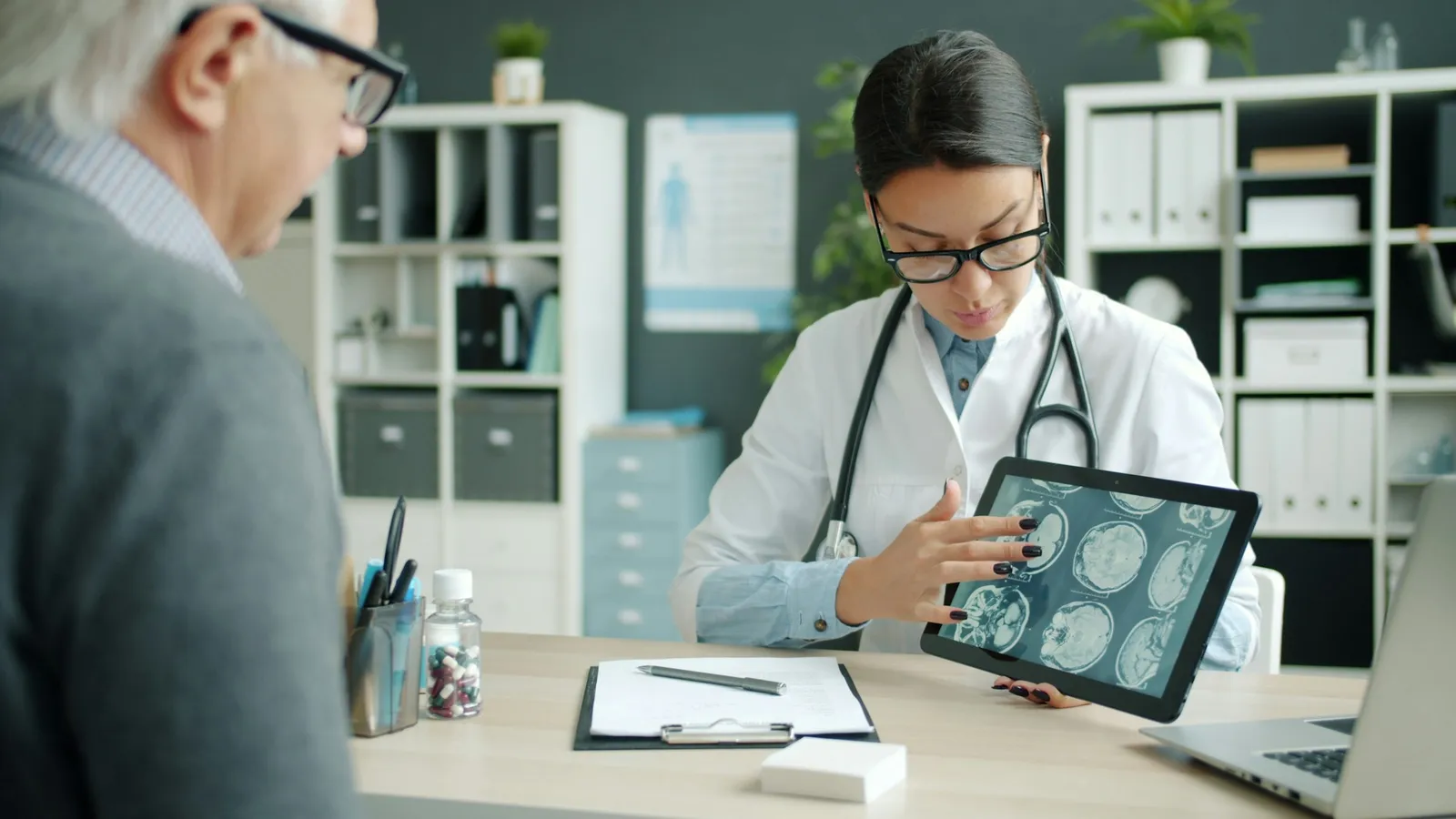 A doctor showing a patient brain scans on a tablet