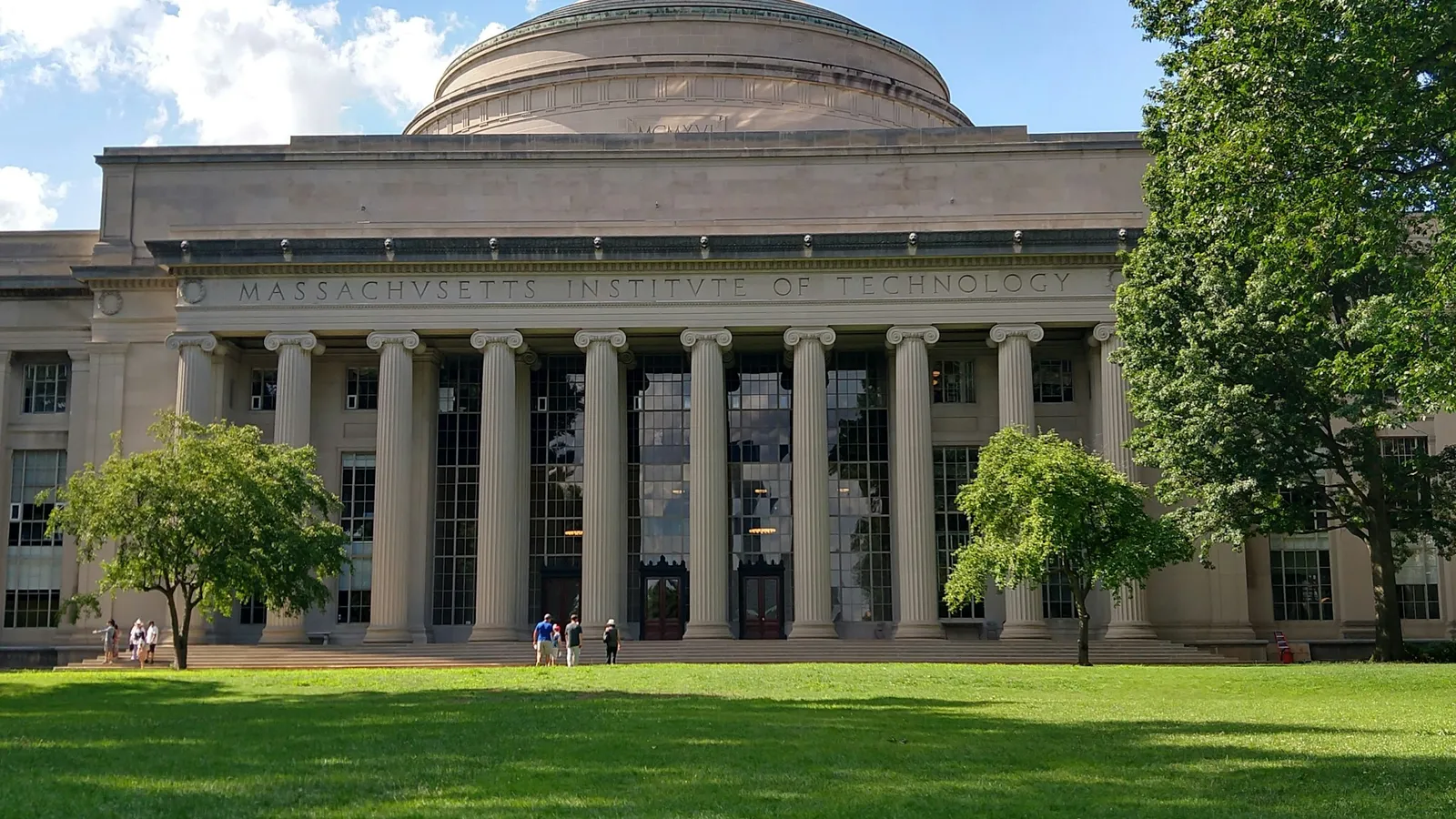 A domed university building with columns behind a lawn