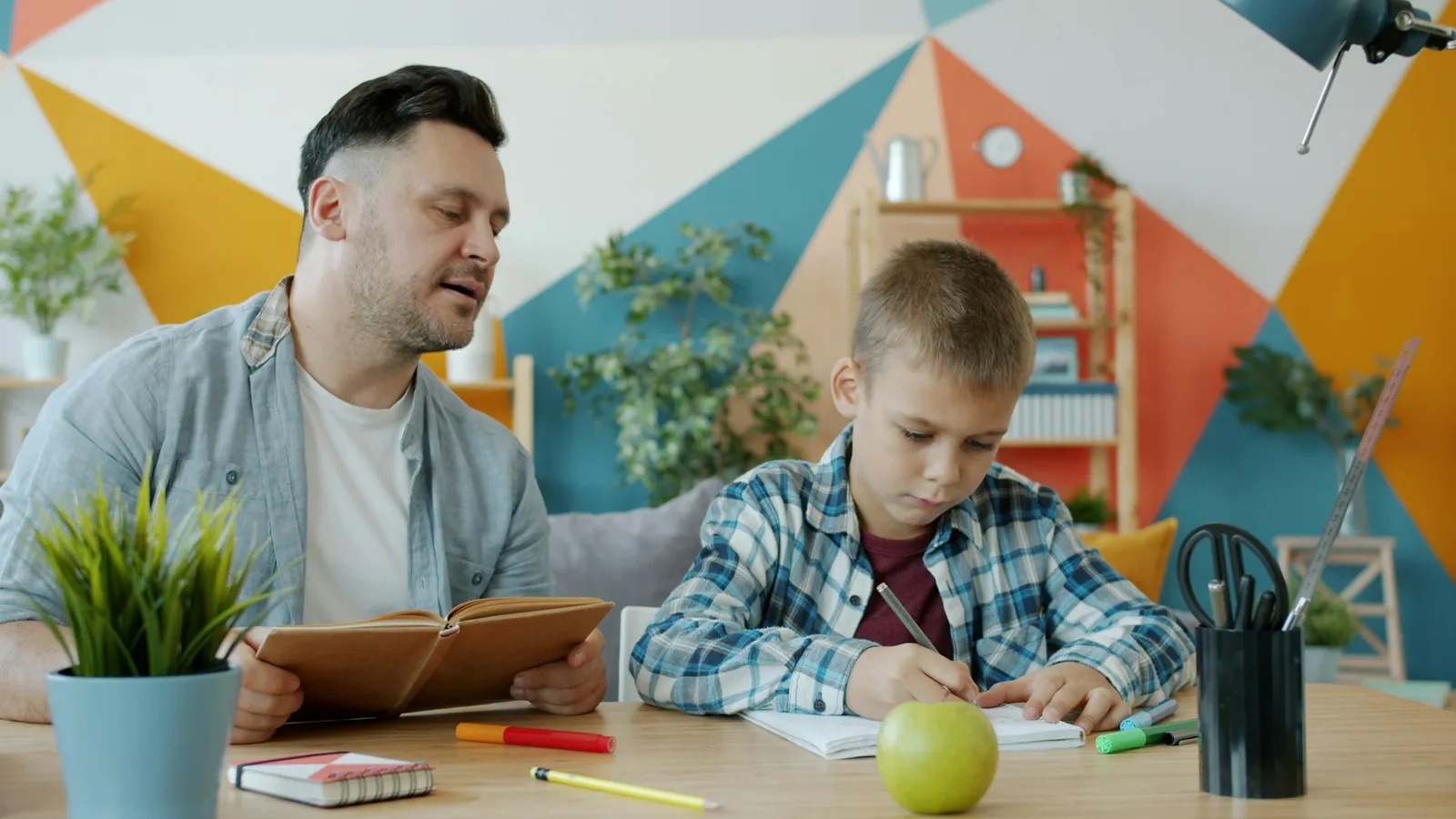 A father helping his son with homework at a desk