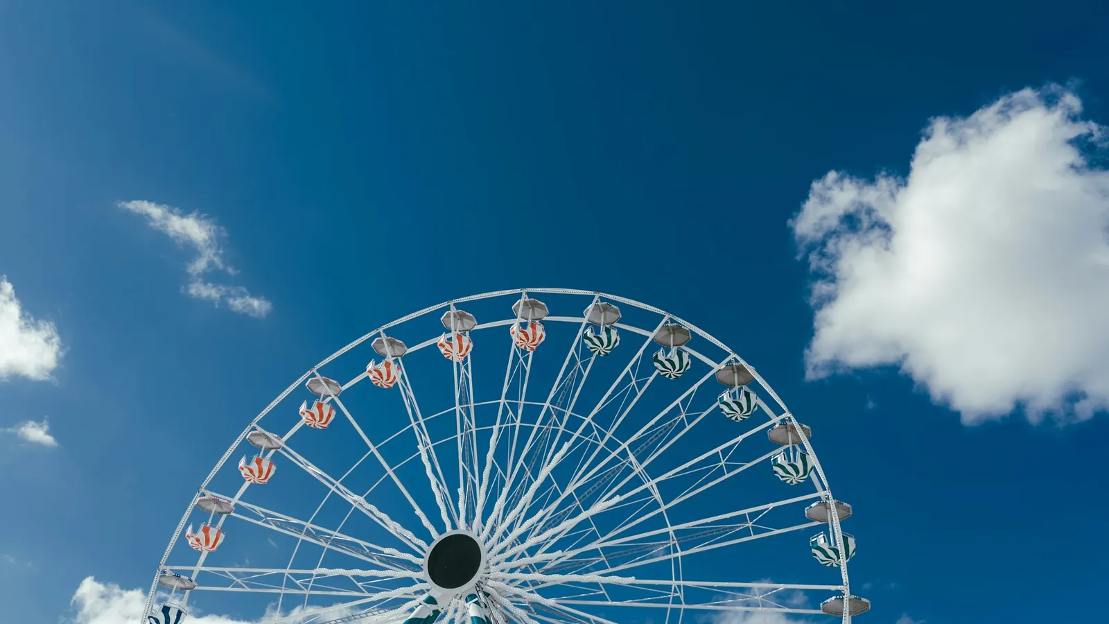 A Ferris wheel against a blue sky with clouds