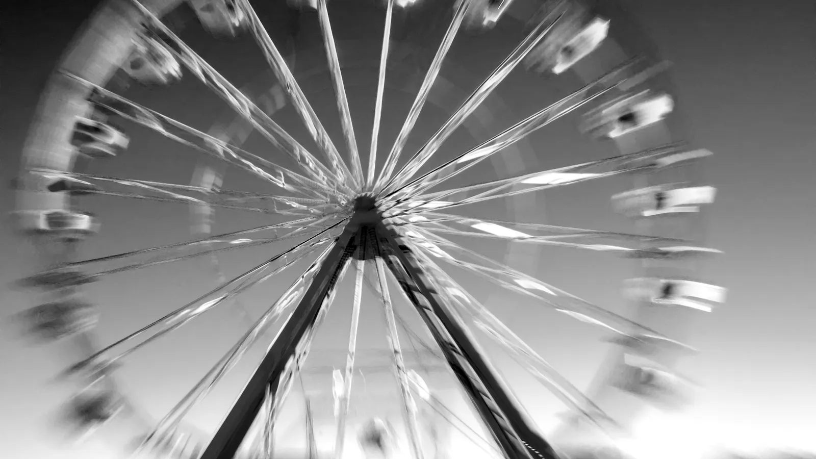 A Ferris wheel blurred by its spin, in black and white