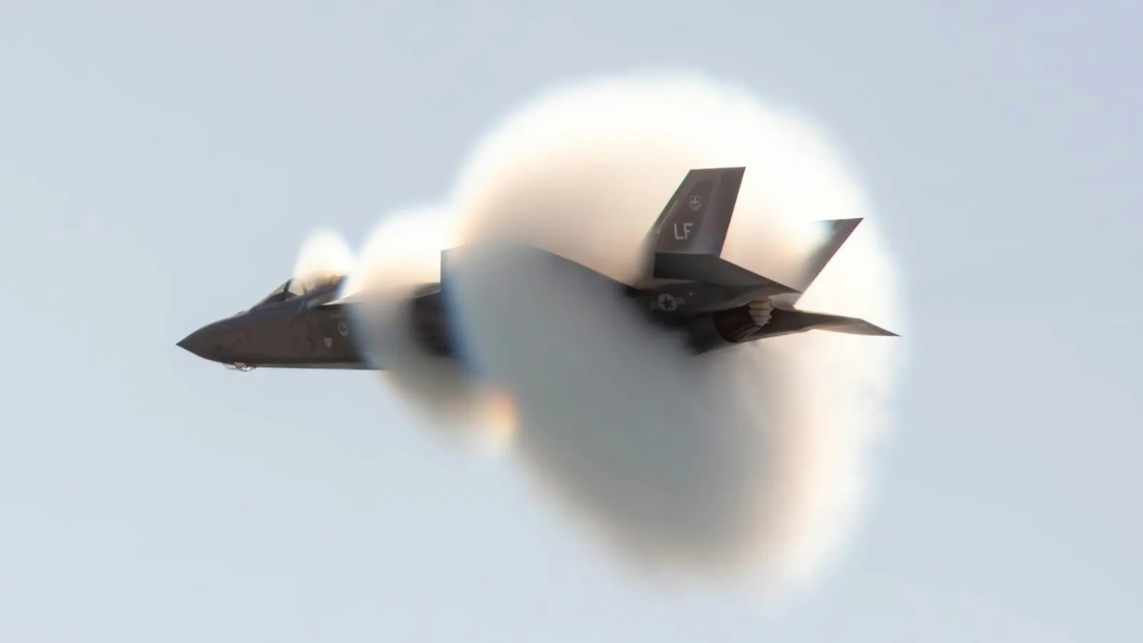 A fighter jet wrapped in a vapour cone at high speed