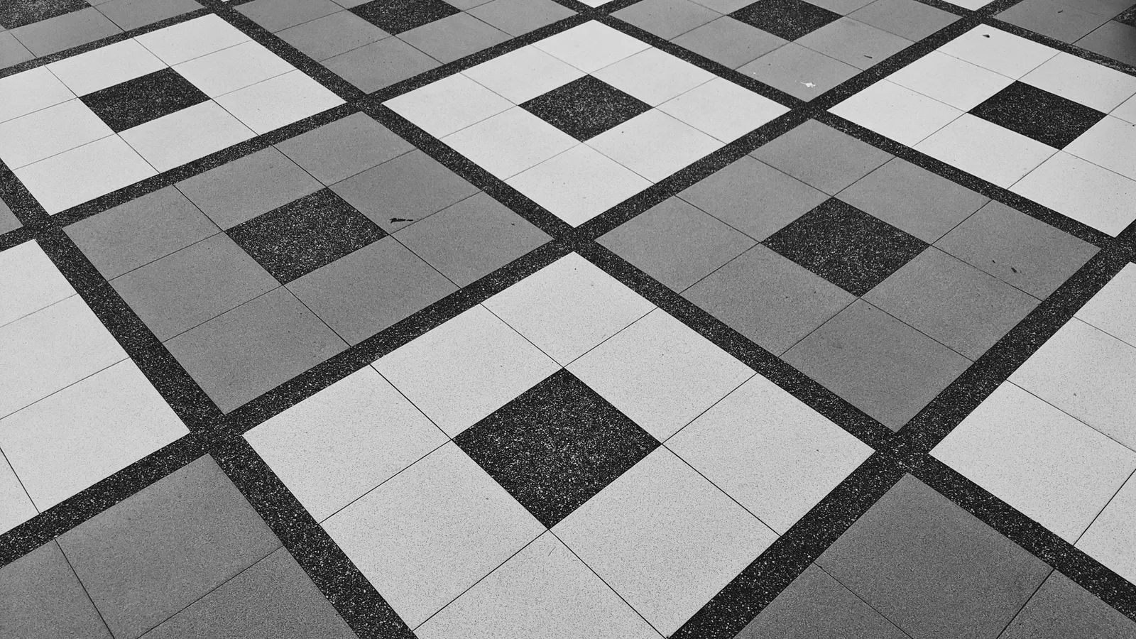 A floor of square grey and white tiles in a diamond pattern
