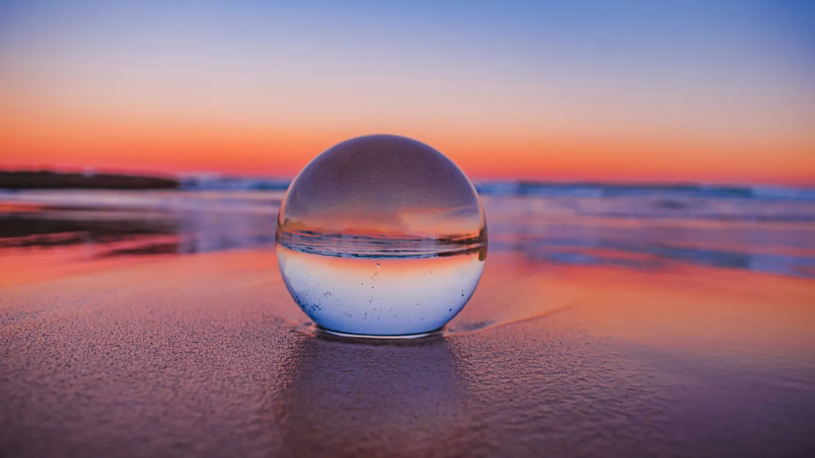 A glass ball showing an upside-down sunset over the sea