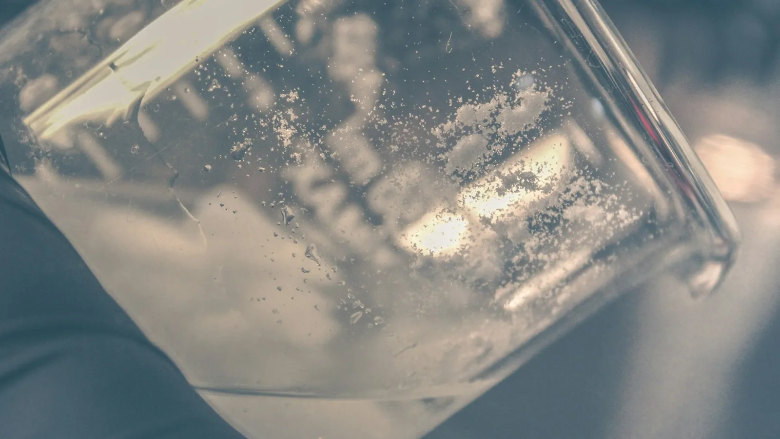 A glass beaker of clear liquid in soft grey light
