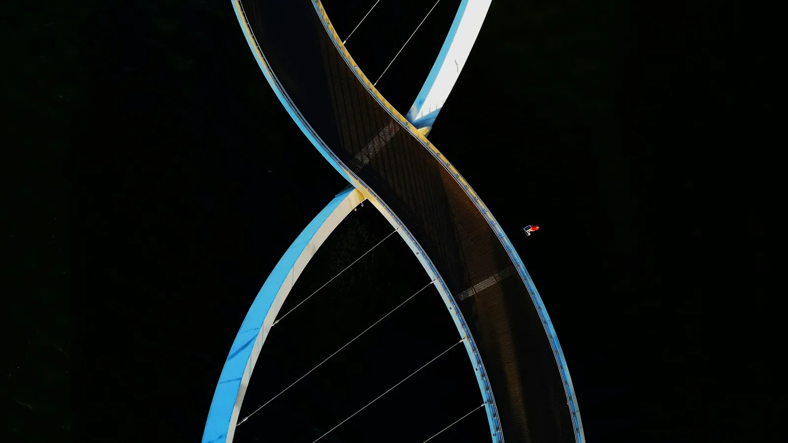 A glass model of a DNA double helix against a black background
