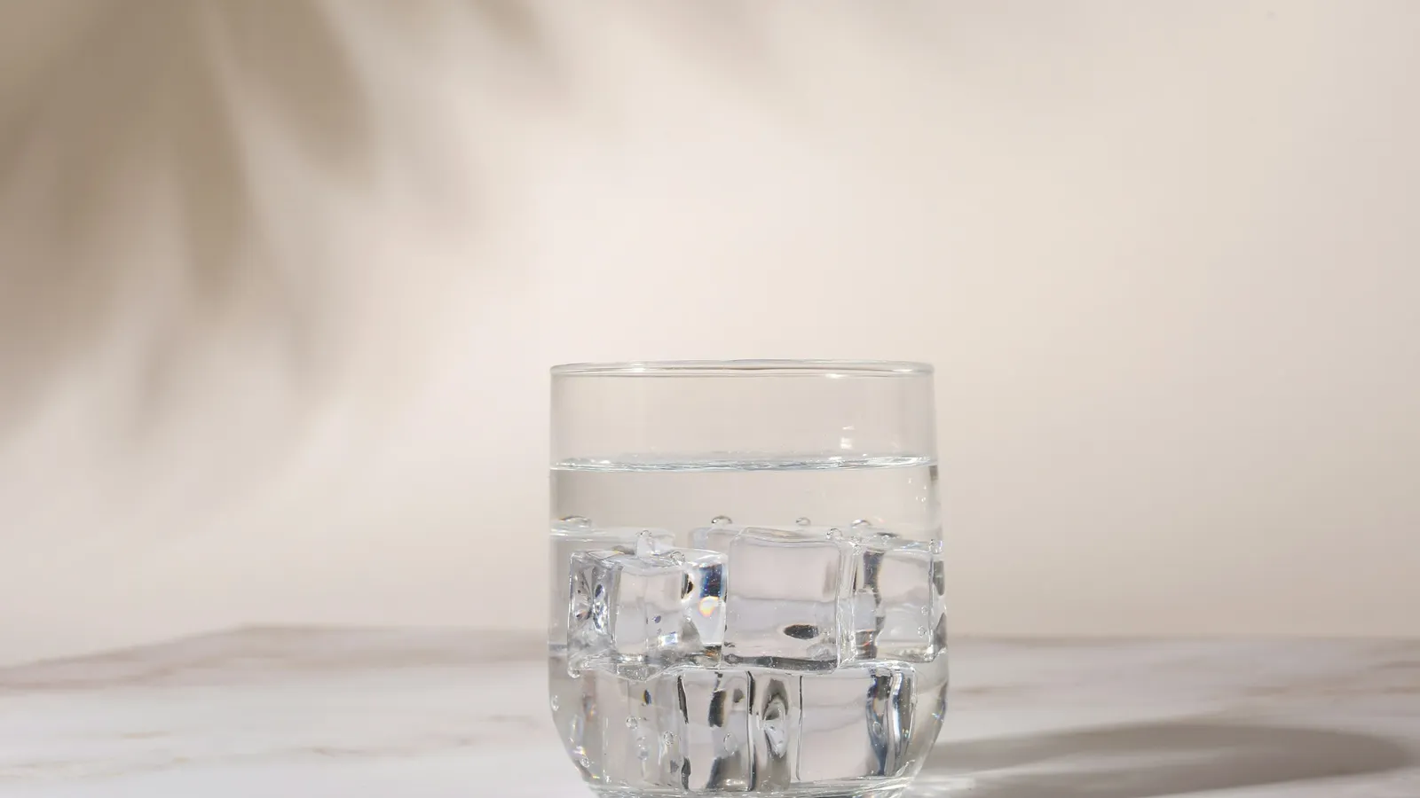 A glass of iced water on a white table in soft light