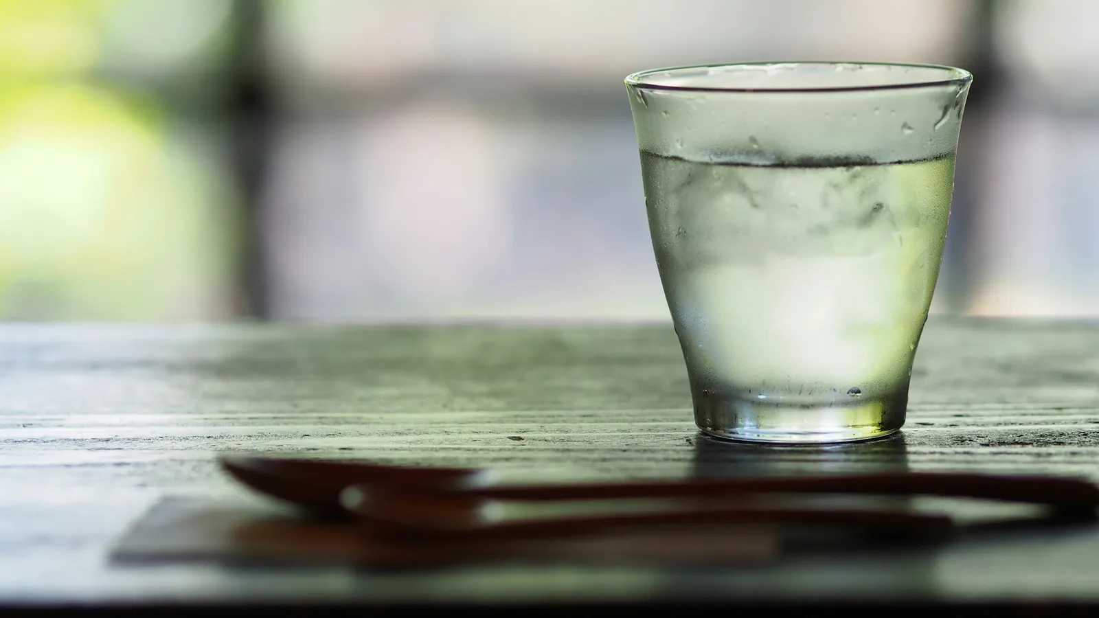 A glass of water on a wooden table in daylight