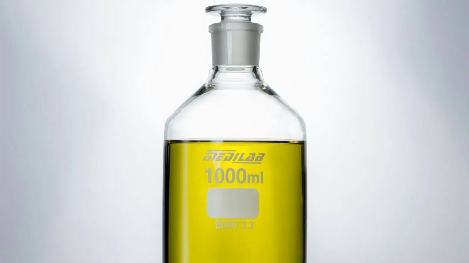A glass reagent bottle of yellow liquid
