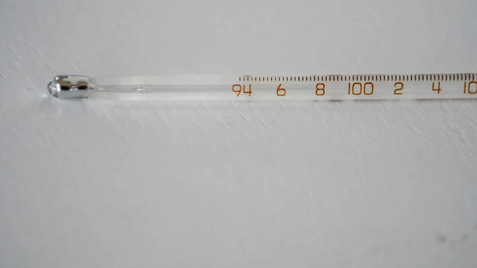 A glass thermometer lying on a white surface