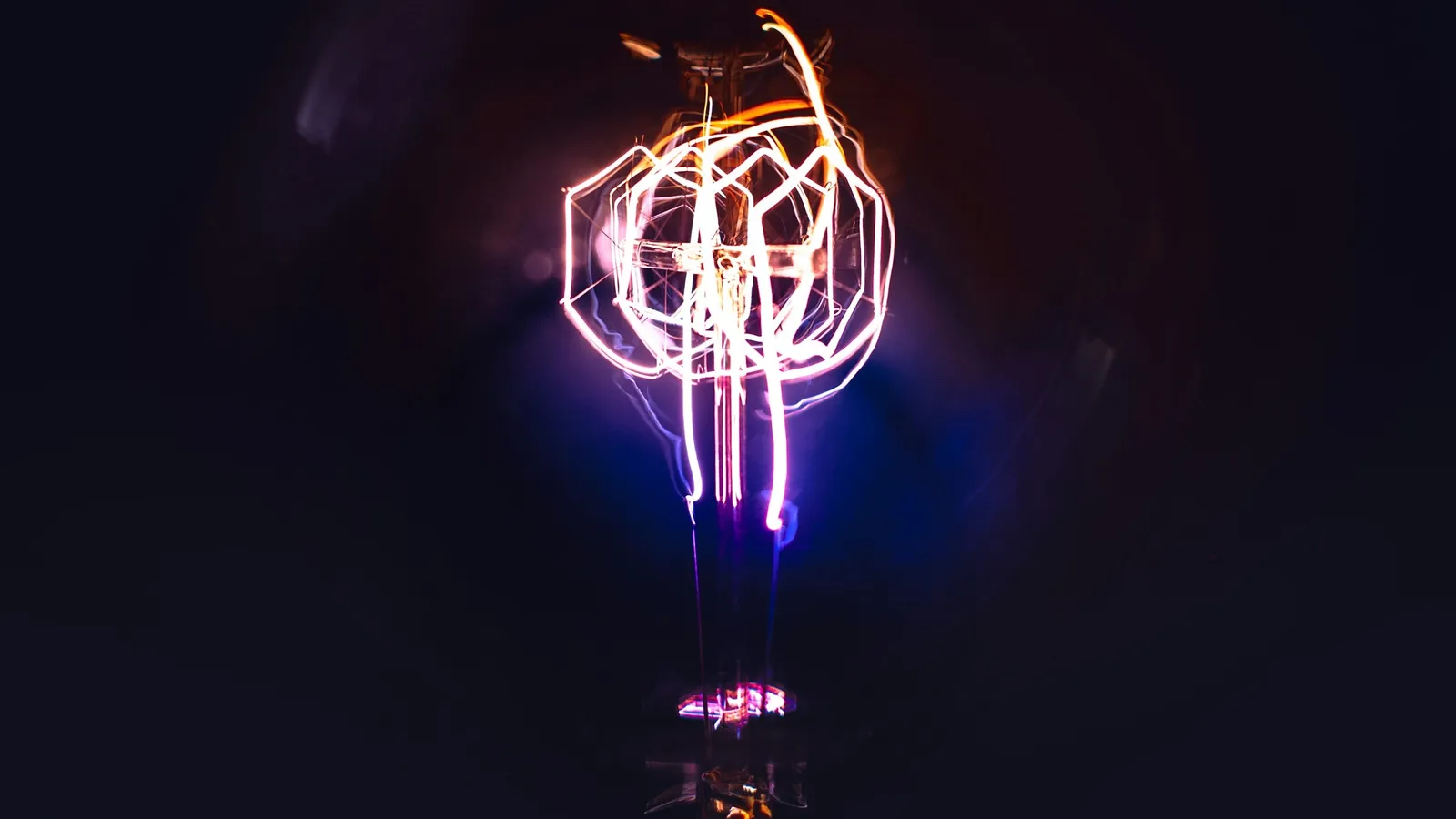 A glowing filament inside a glass bulb in the dark