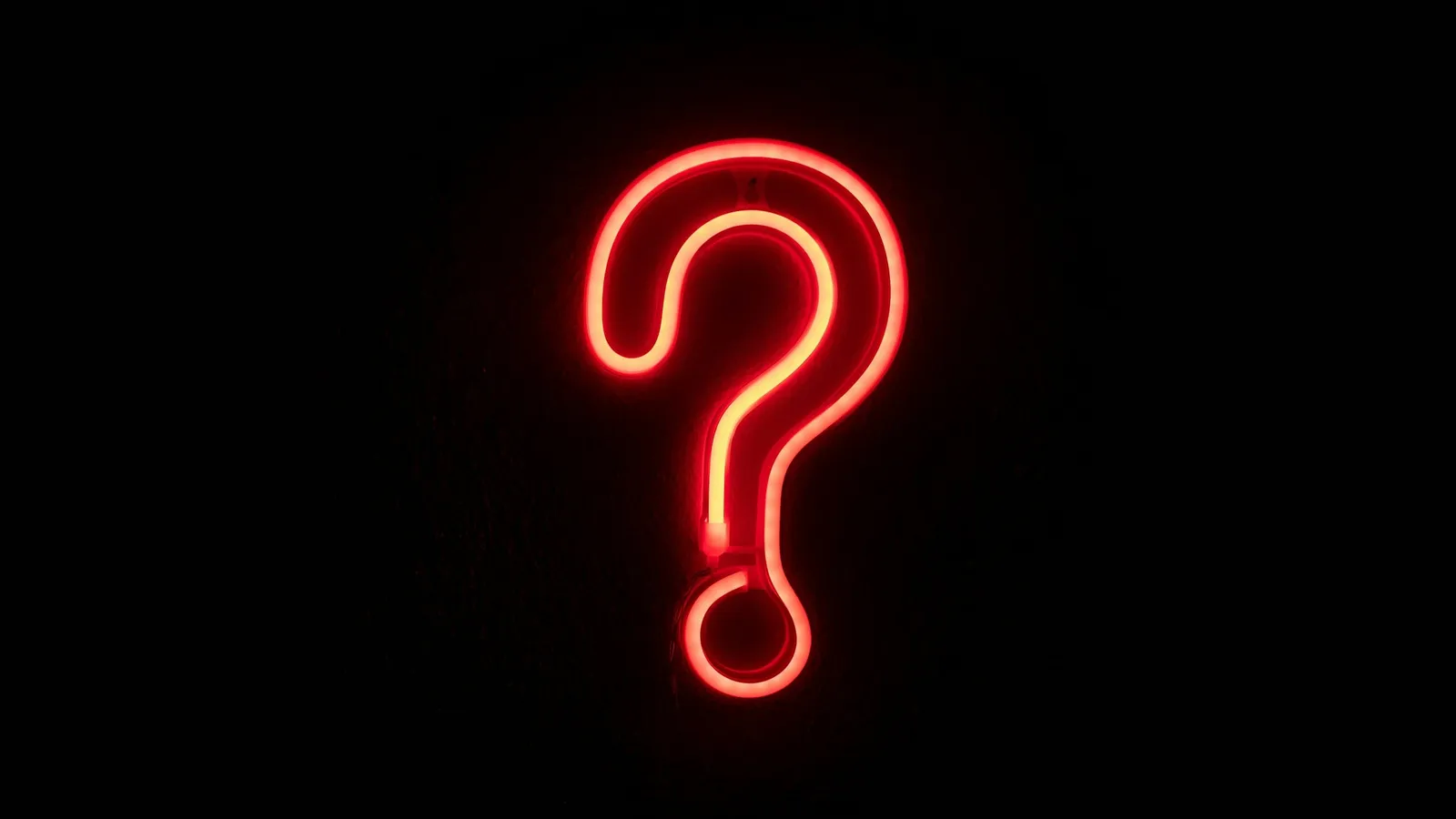A glowing red neon question mark in the dark