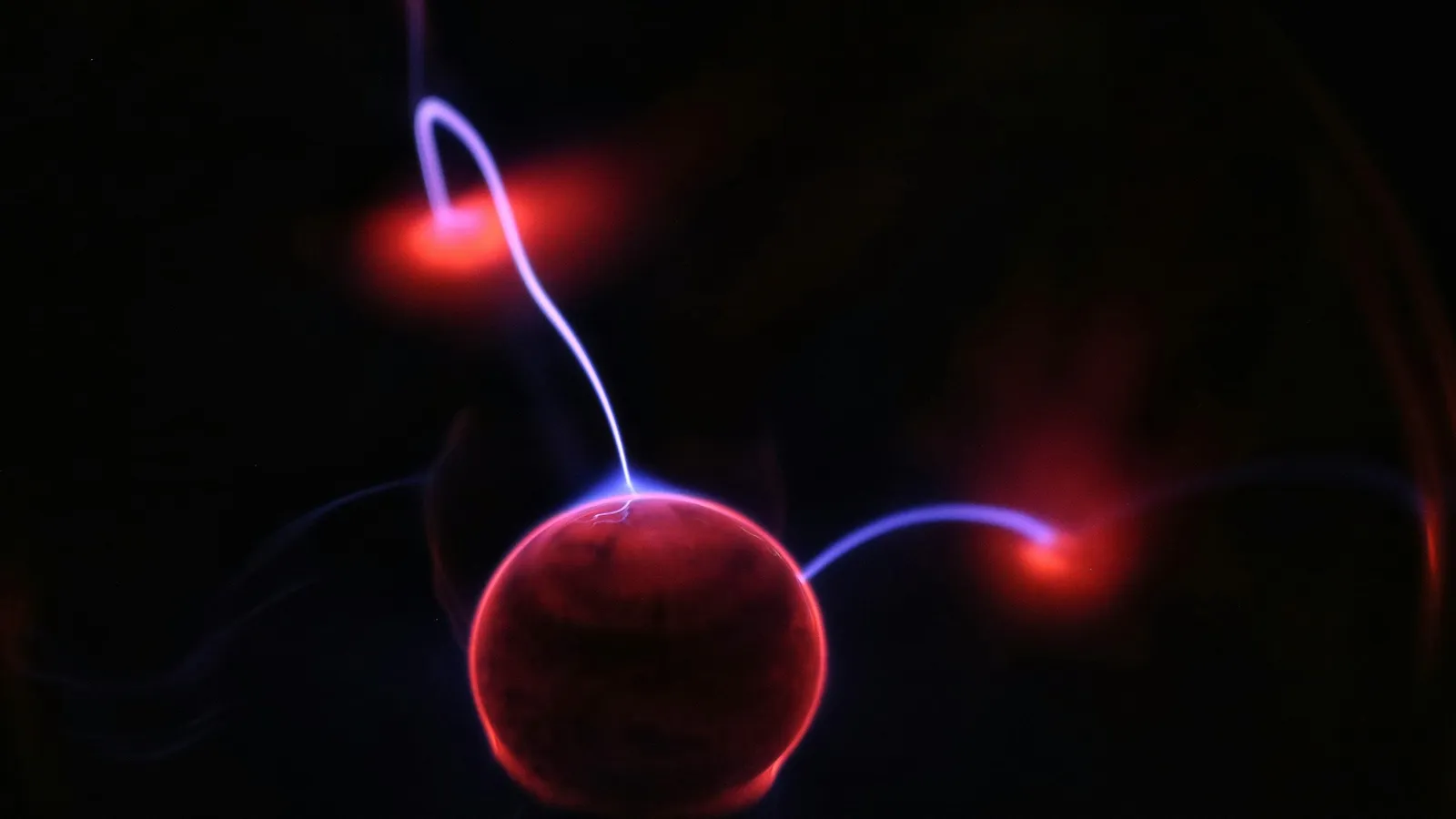 A glowing red sphere with a curling trail of light against black