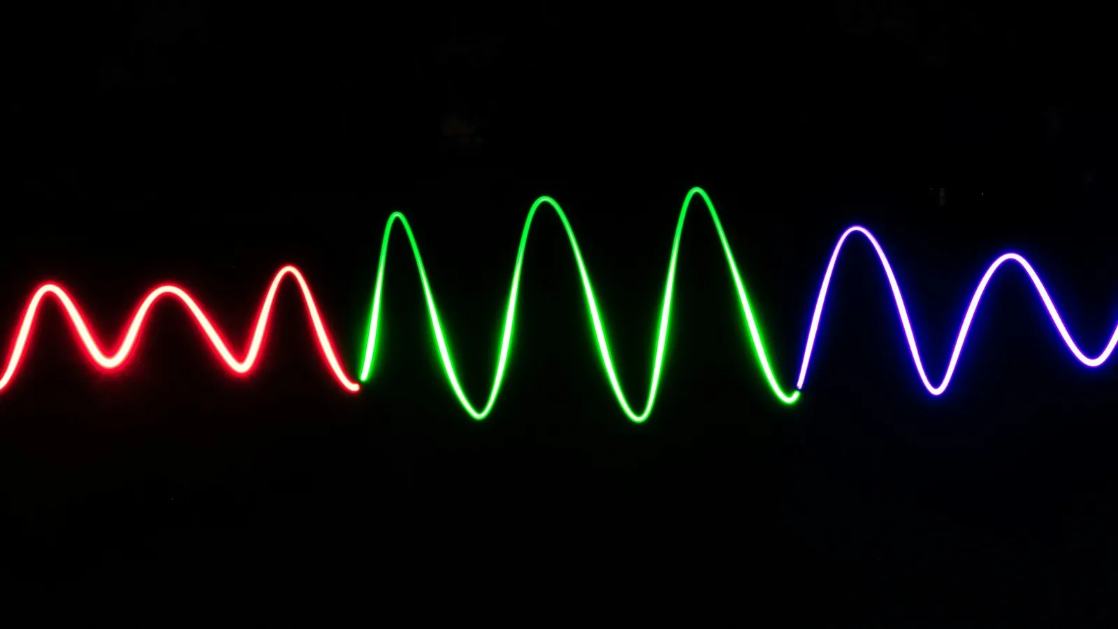 A glowing wave of red, green and blue light against black