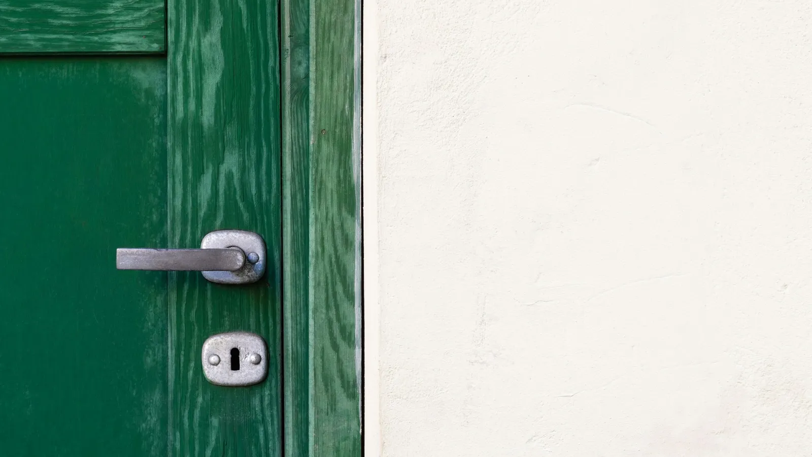 A green door with its handle far from the hinge