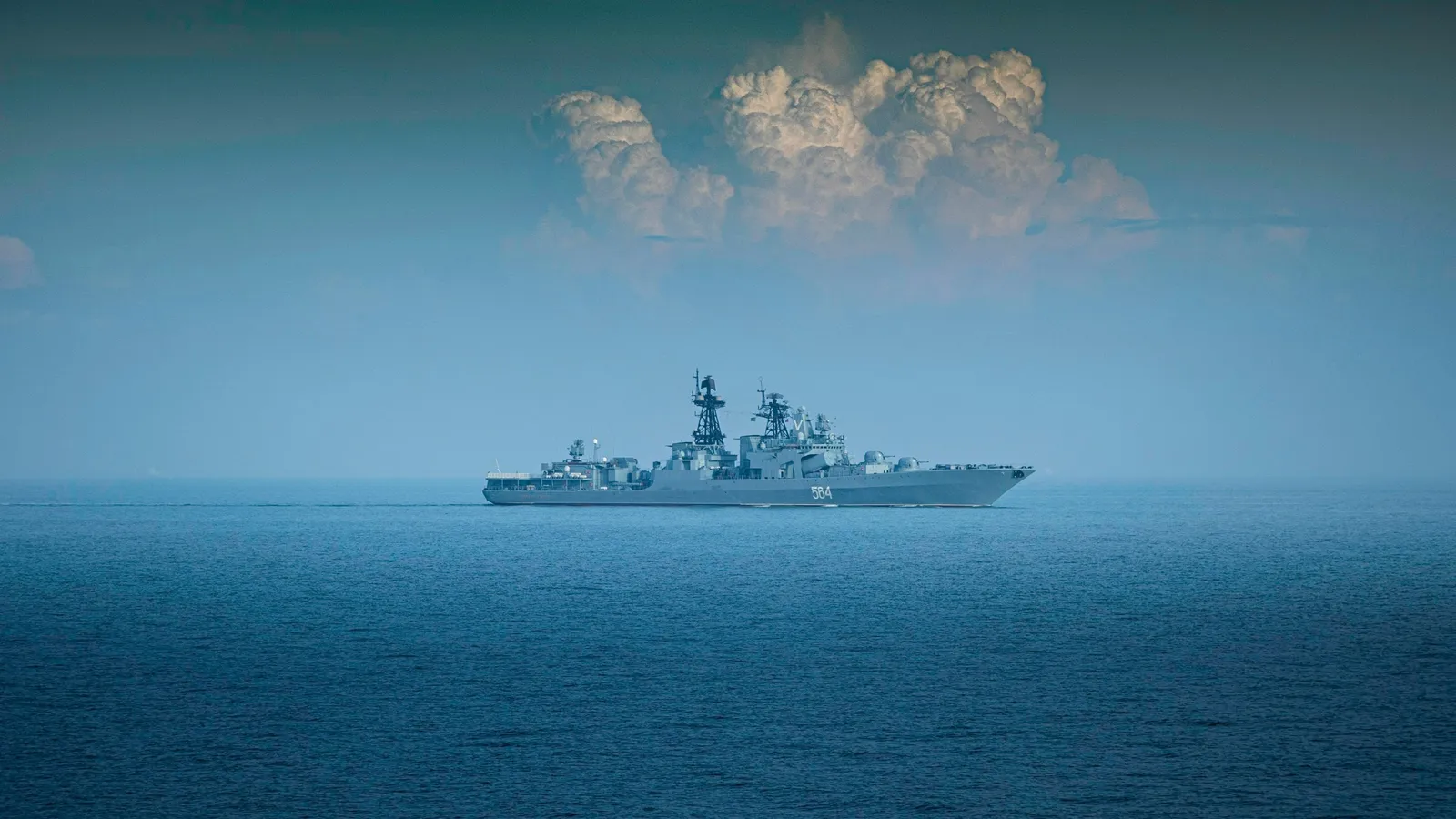 A grey naval ship on calm blue sea