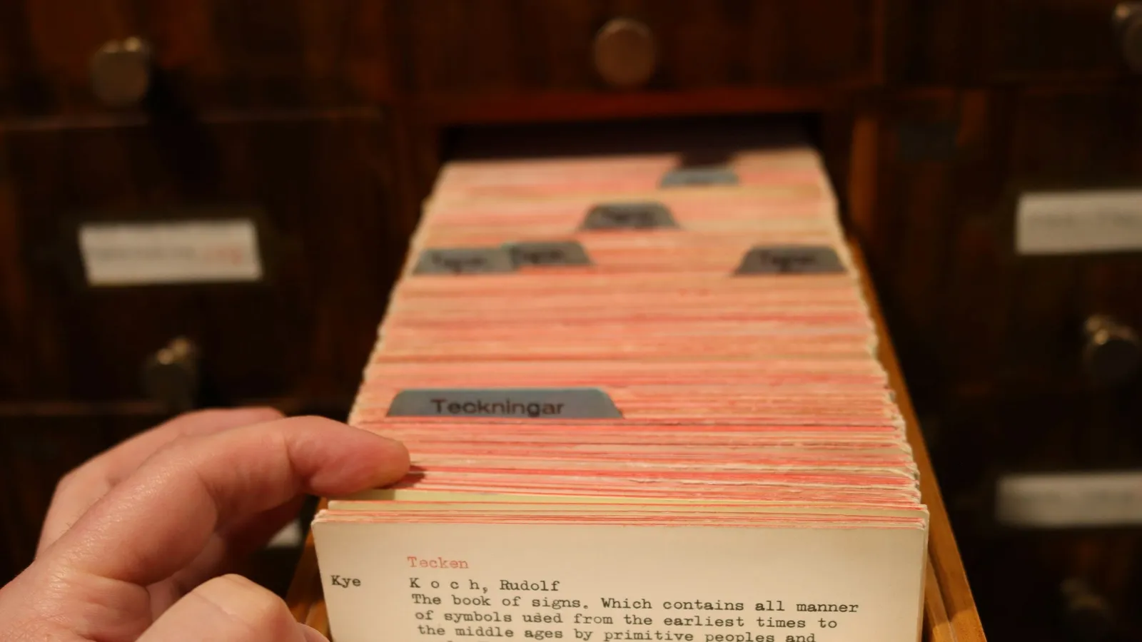 A hand flipping through a drawer of index cards